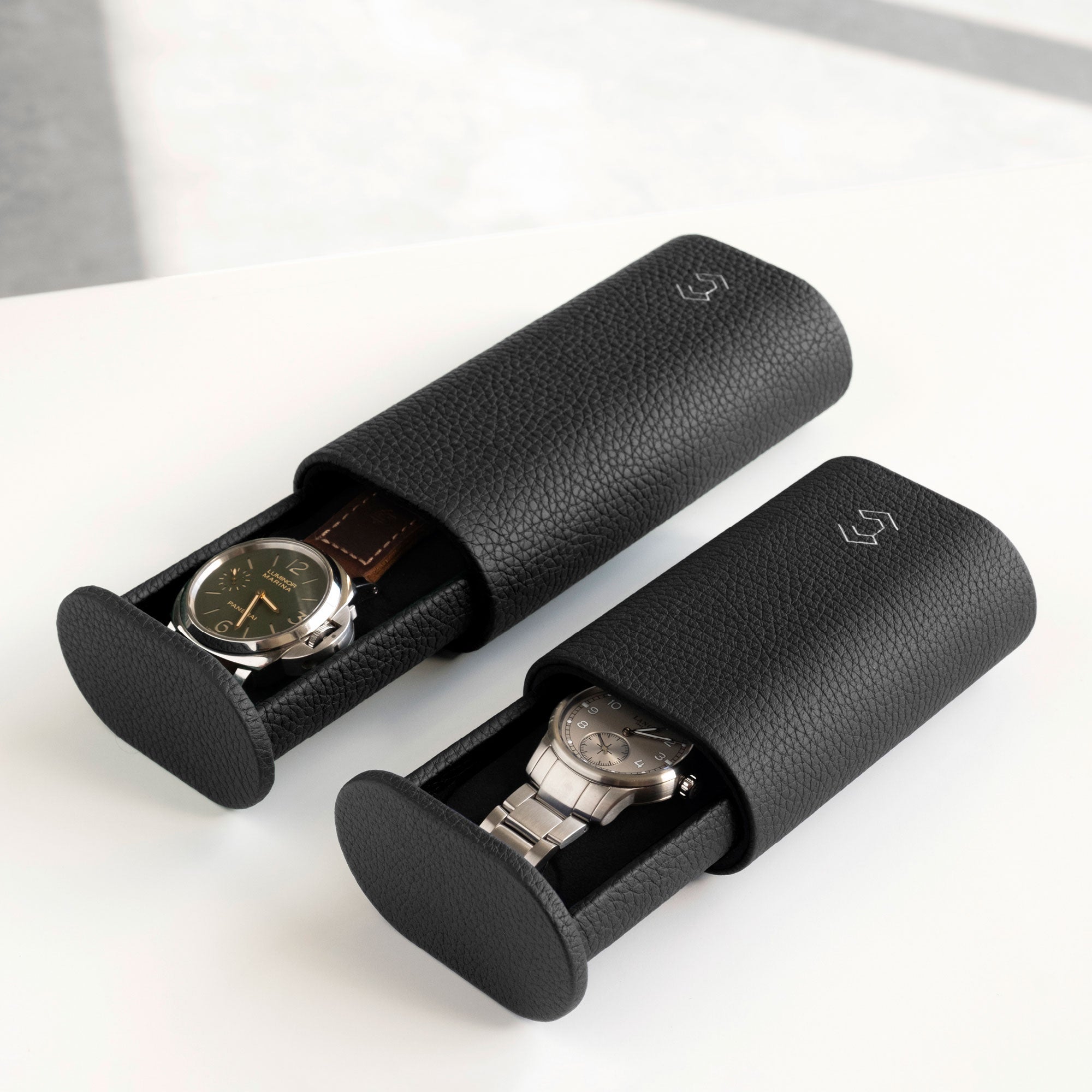 Lifestyle photo of two Oscar watch rolls in black leather side by side. The Oscar 1 Tall for watches with a watch strap on the left and the Oscar 1 for watches with a metal bracelet on the right