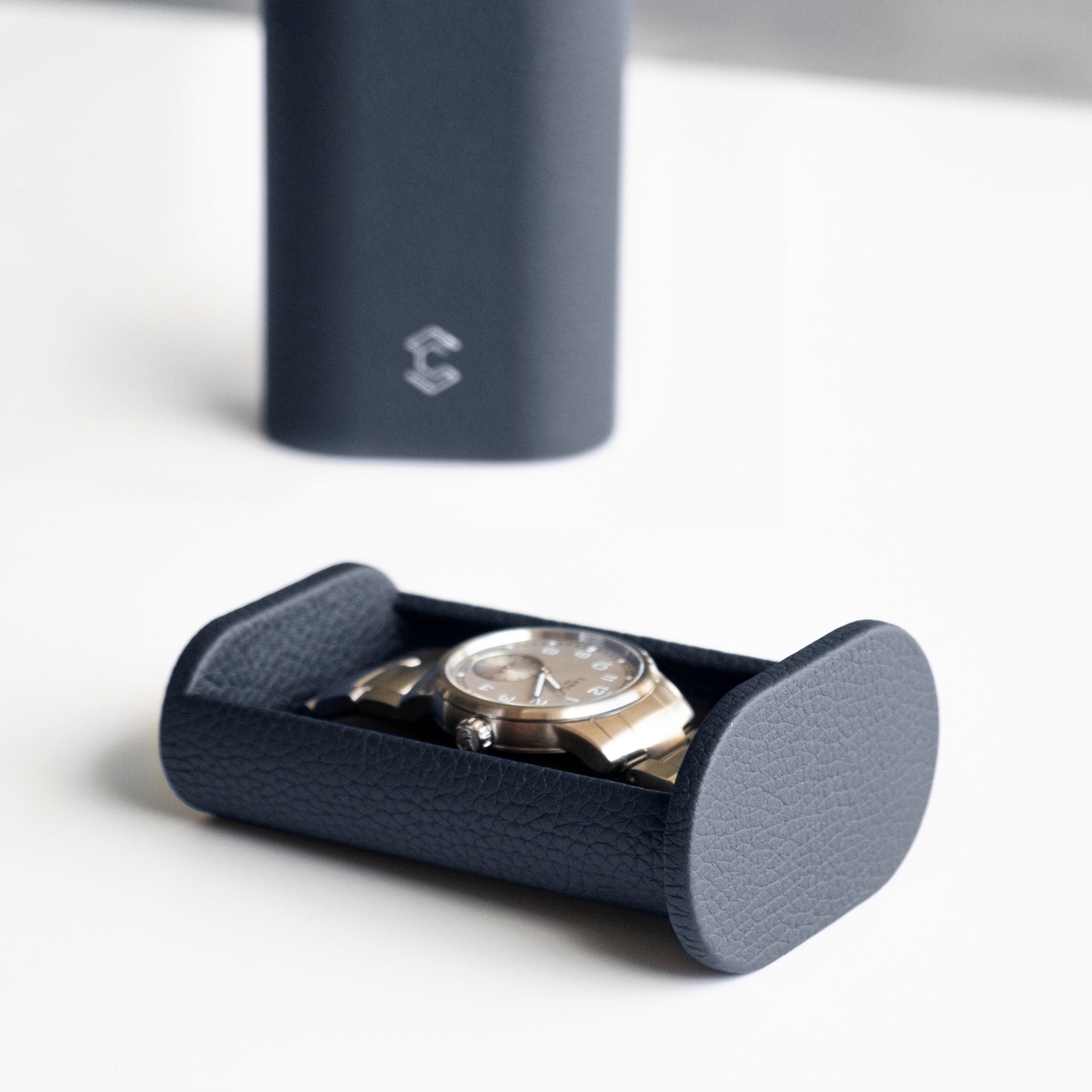 Closeup lifestyle photo of Oscar 1 Watch roll case in marine leather holding a men's watch with a metal bracelet.