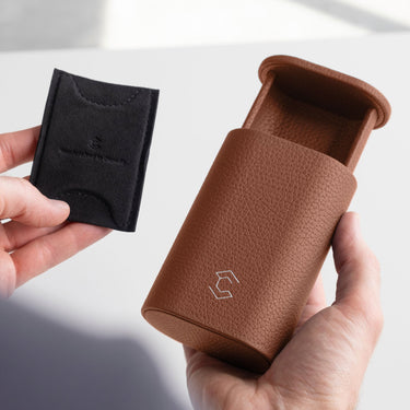 Man holding tan leather Oscar Watch roll in one hand and the card insert to hold the watch in place in the other hand.